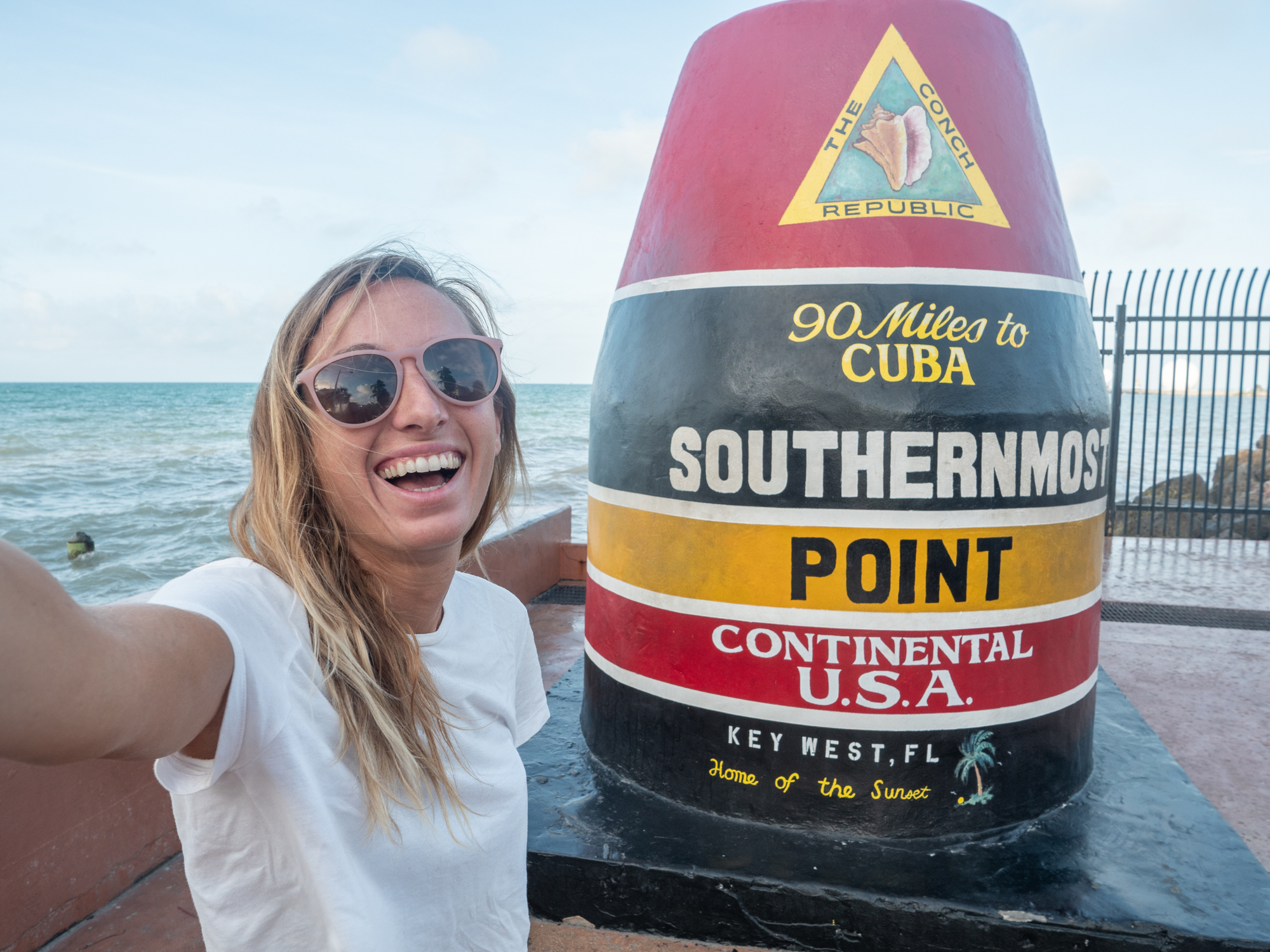 Woman taking selfie with Southernmost point in Key West USA