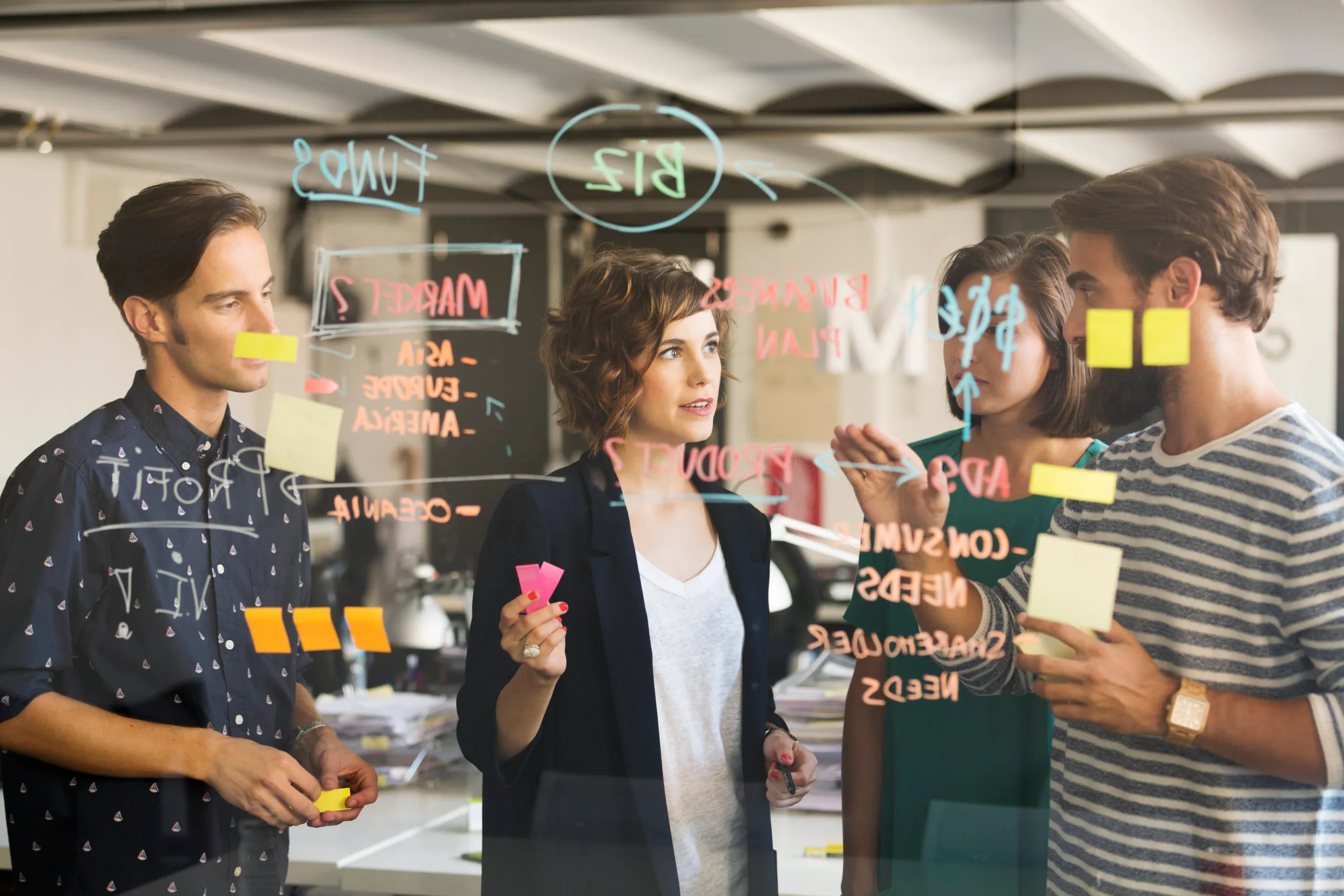 Business people discussing over plan on glass wall in office