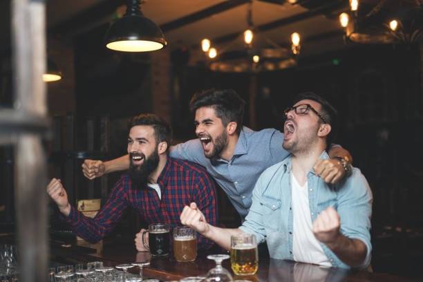 Men watching football in bar and drink beer