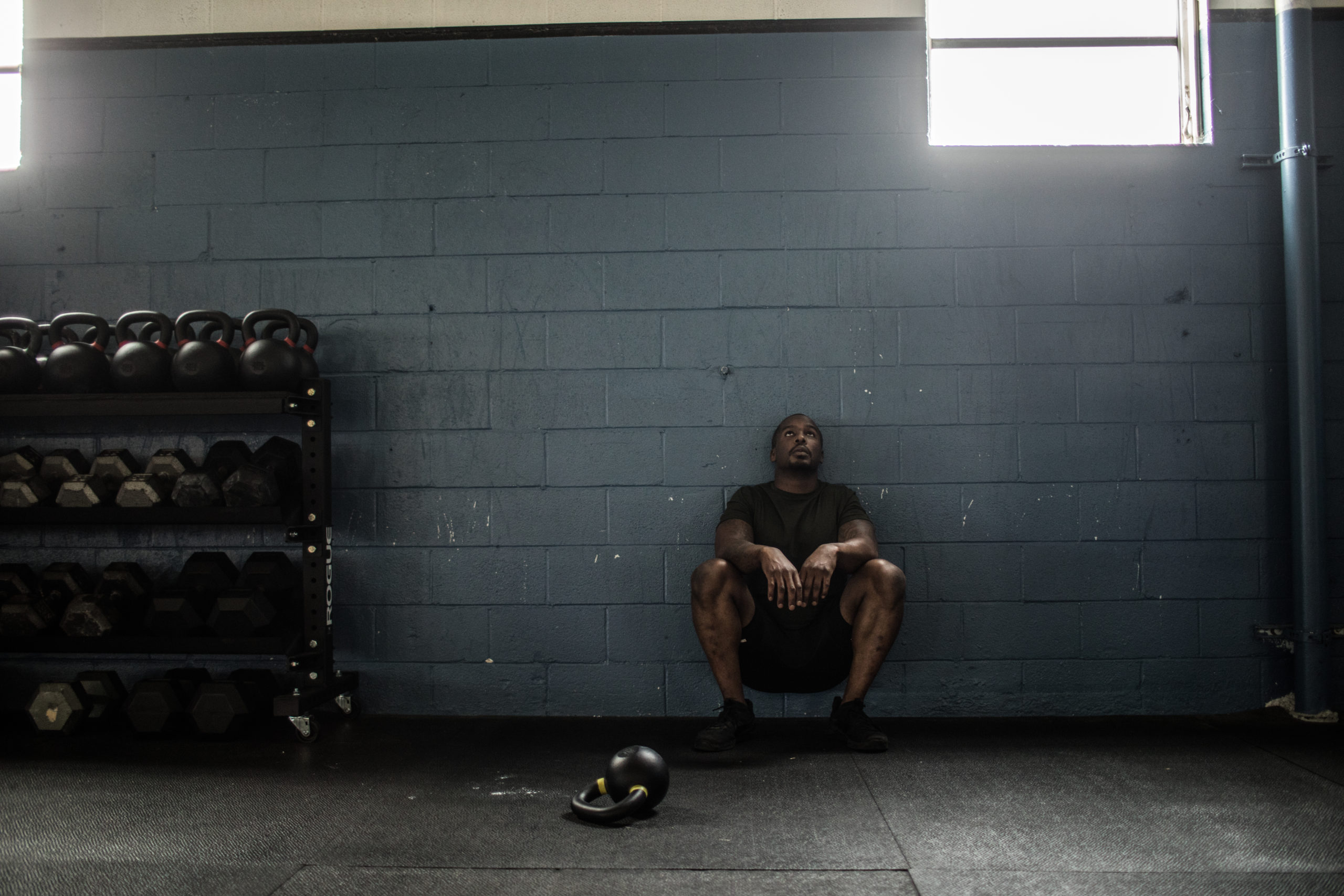 Man resting against wall at cross training gym