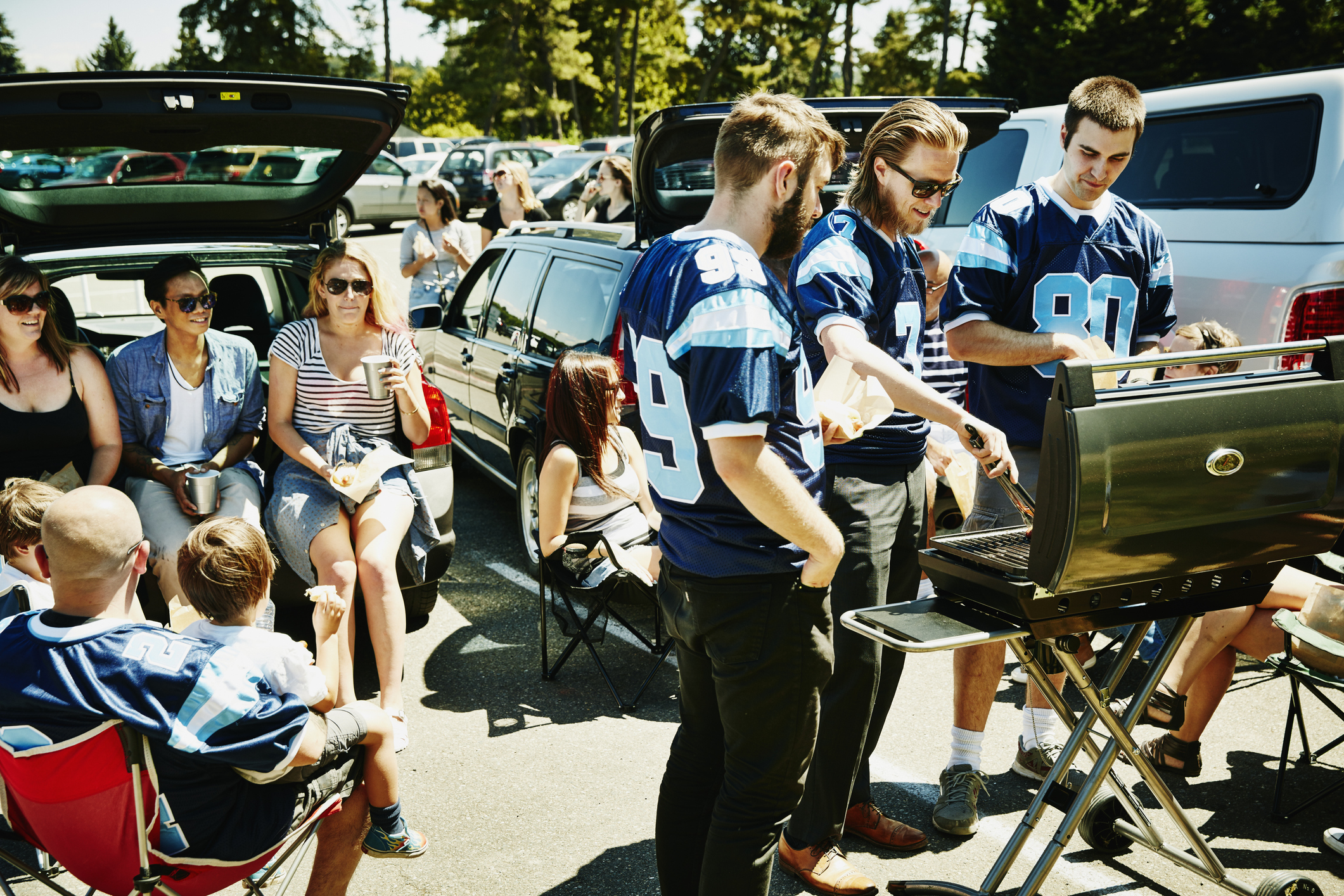 Friends barbecuing during tailgating party in football stadium parking lot