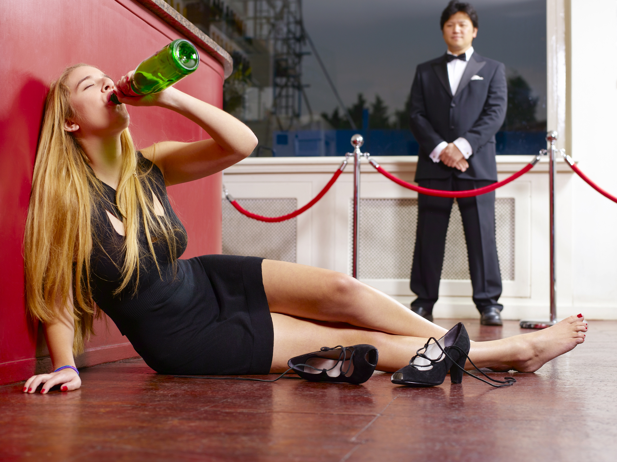 Teenager drinking Champagne on nightclub floor
