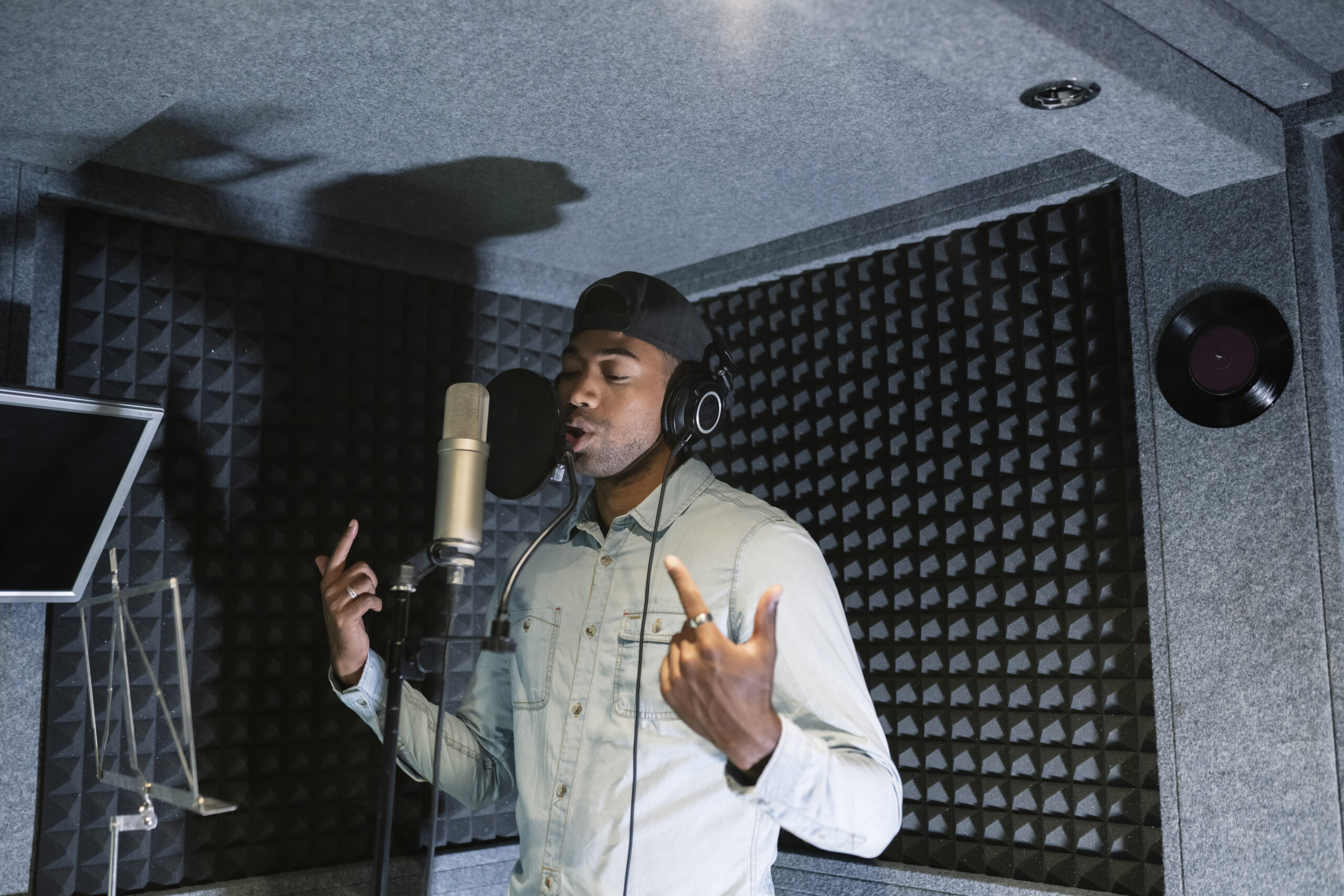 young african american male rapper, songwriter recording song in studio