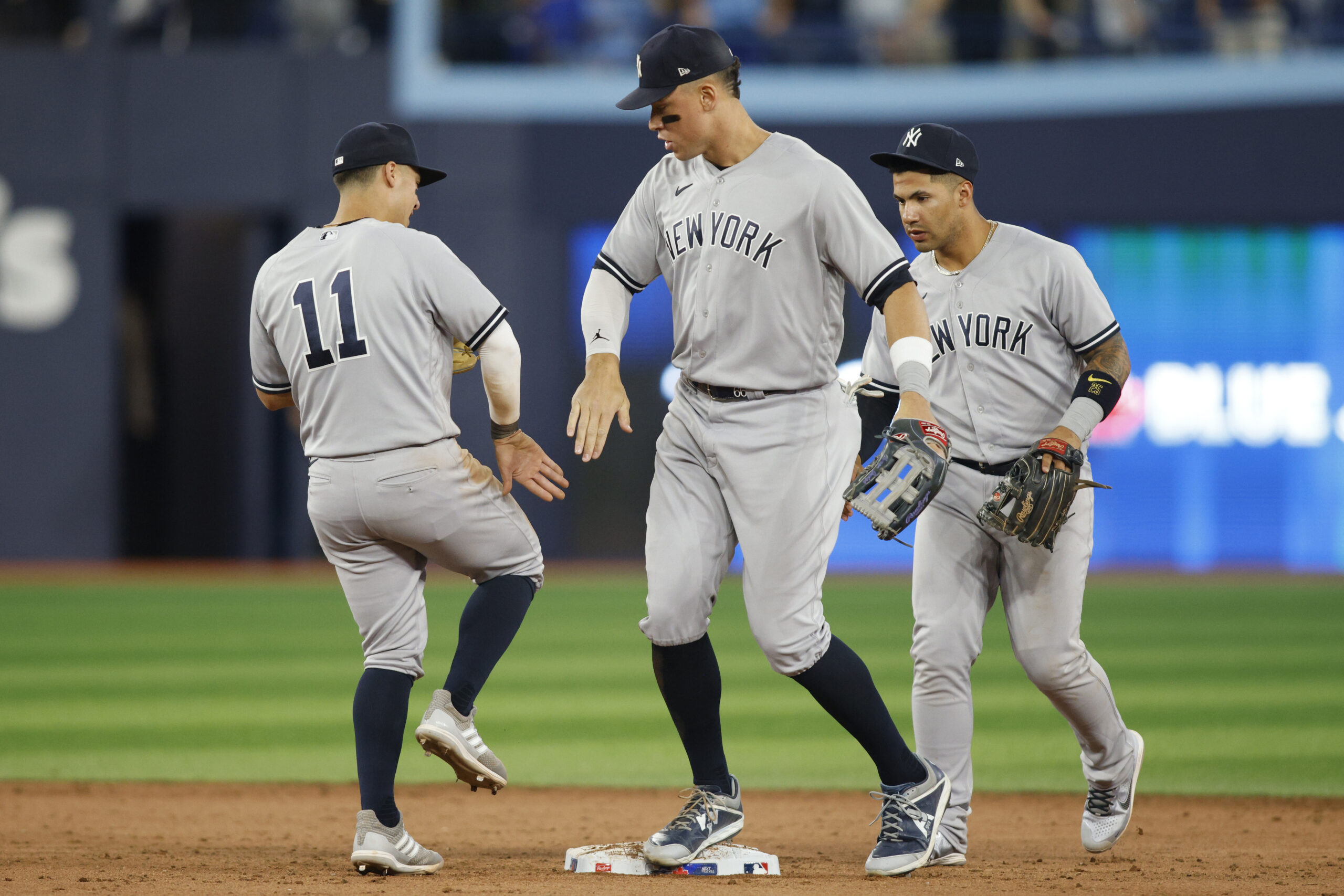 TORONTO, ON - MAY 15: Aaron Judge #99, Anthony Volpe #11, and  Gleyber Torres #25 of the New York Yankees celebrate their MLB game victory over the Toronto Blue Jays at Rogers Centre on May 15, 2023 in Toronto, Canada. (Photo by Cole Burston/Getty Images)