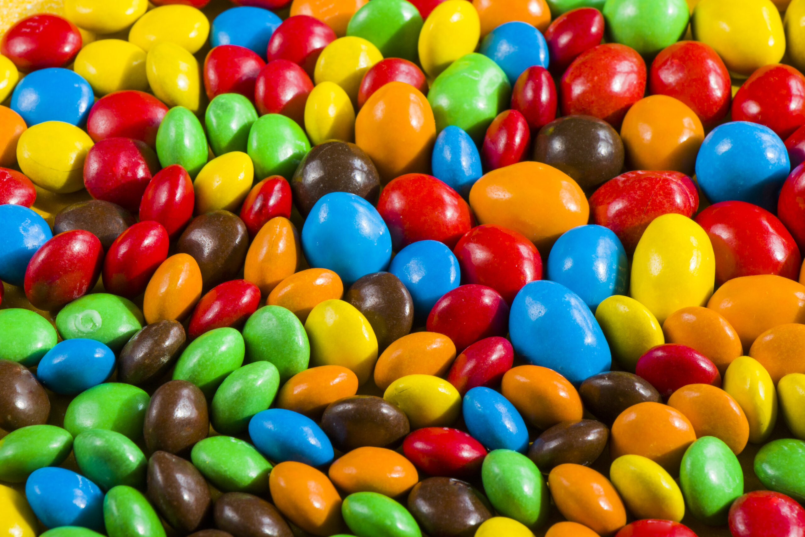 M&M's candy on the yellow background, colorful candy and multicolored gradient