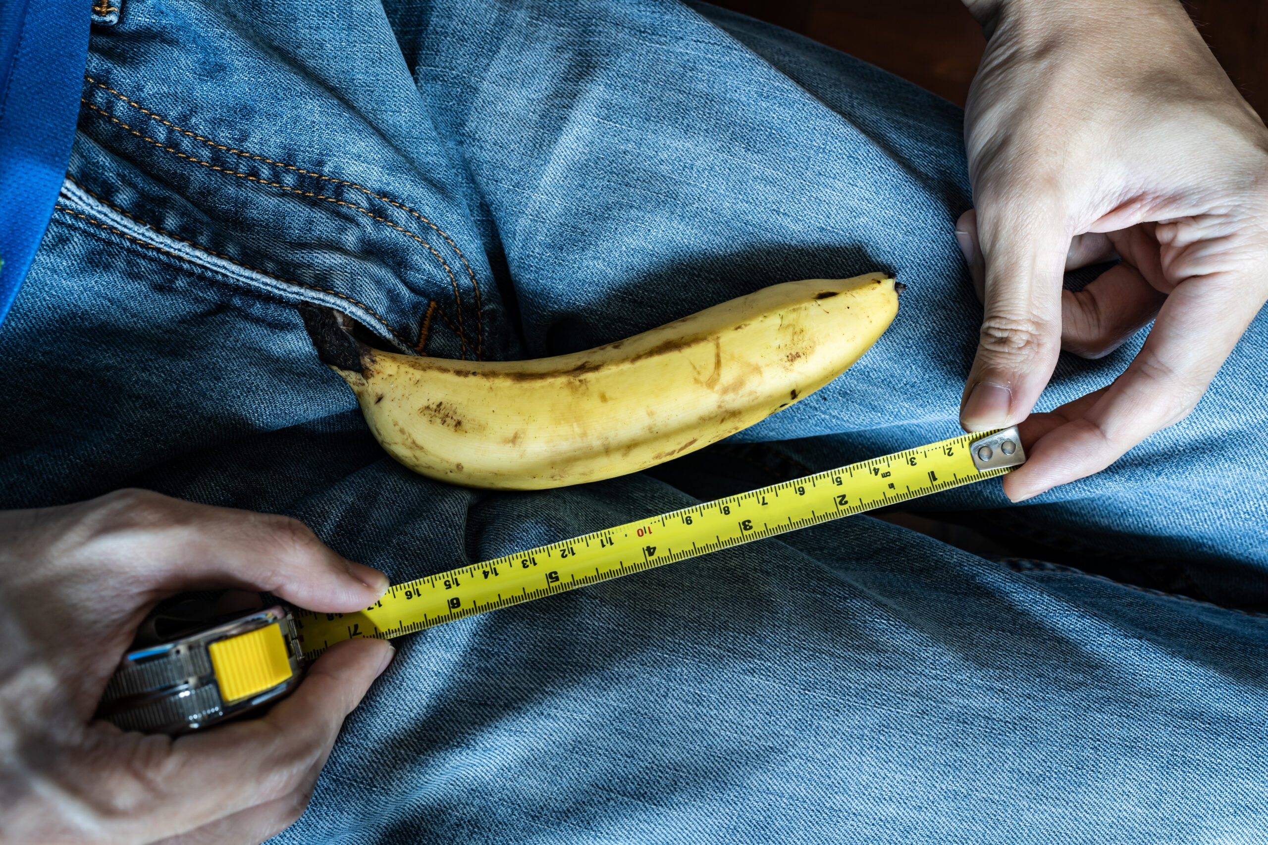 A man measures a size of a banana with measure tape