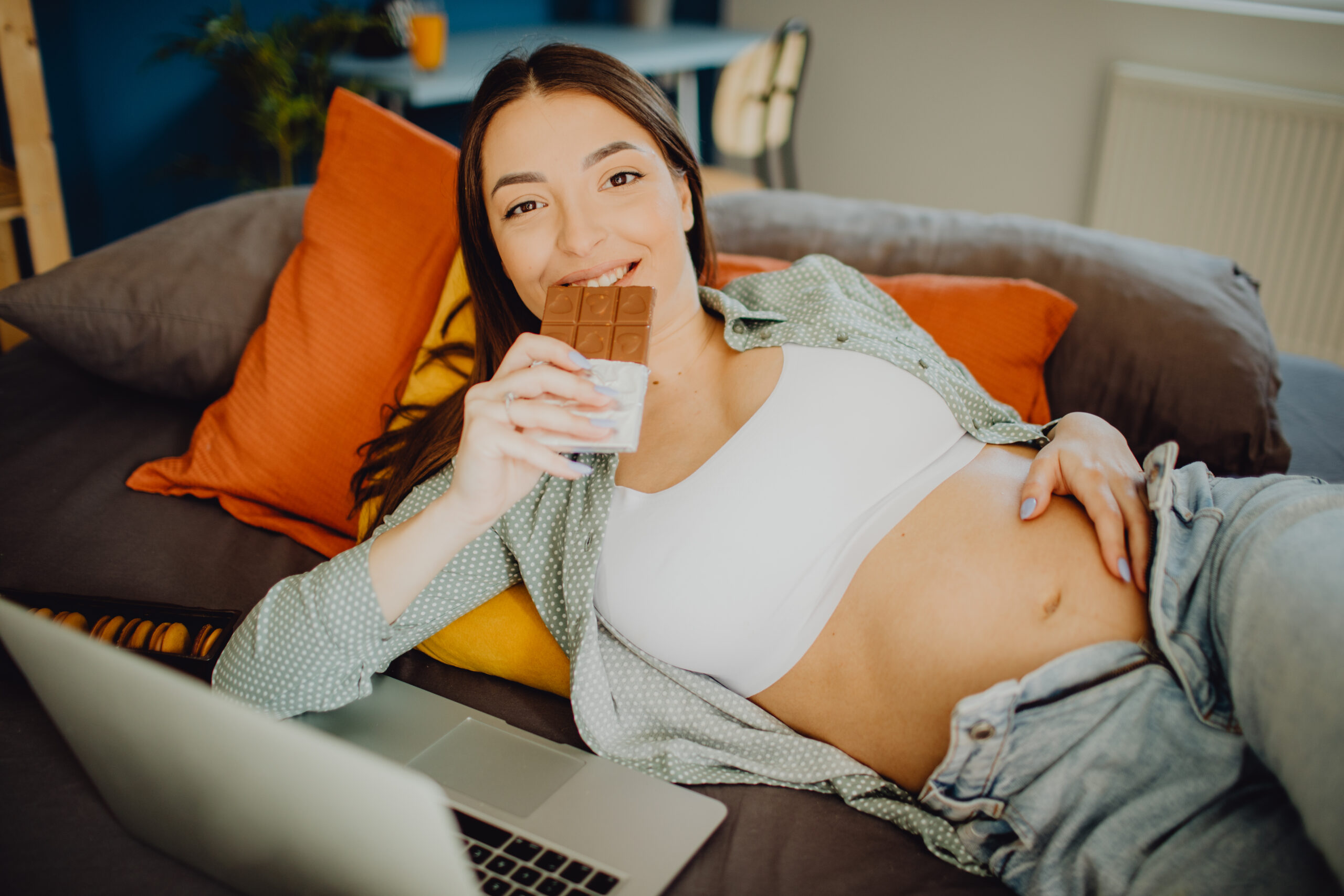 Portrait of a pregnant woman eating chocolate while relaxing in her bed