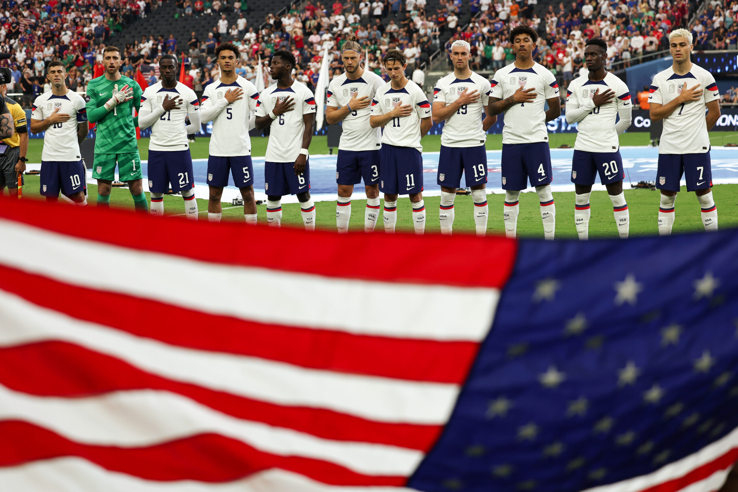 LAS VEGAS, NEVADA - JUNE 18: The USMNT sing the National Anthem in front the USA flag during the CONCACAF Nations League Final between Canada v United States at Allegiant Stadium on June 18, 2023 in Las Vegas, Nevada. (Photo by Matthew Ashton - AMA/Getty Images)