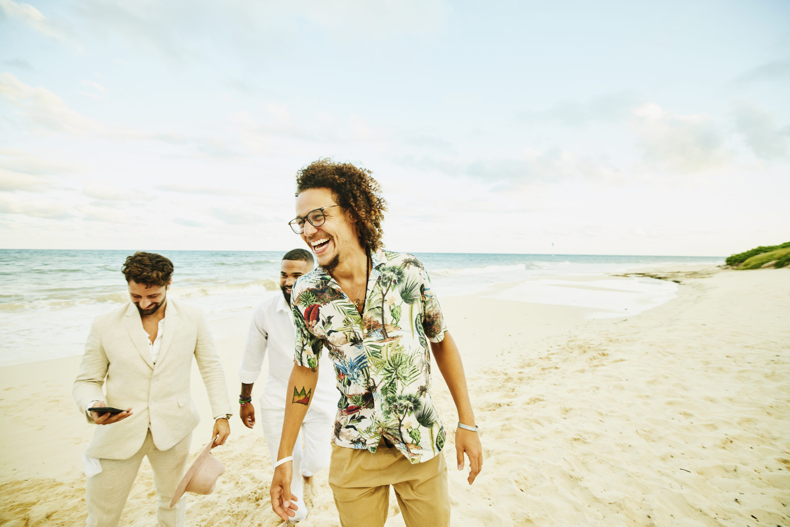 Medium wide shot of laughing man hanging out with friends after tropical beach wedding