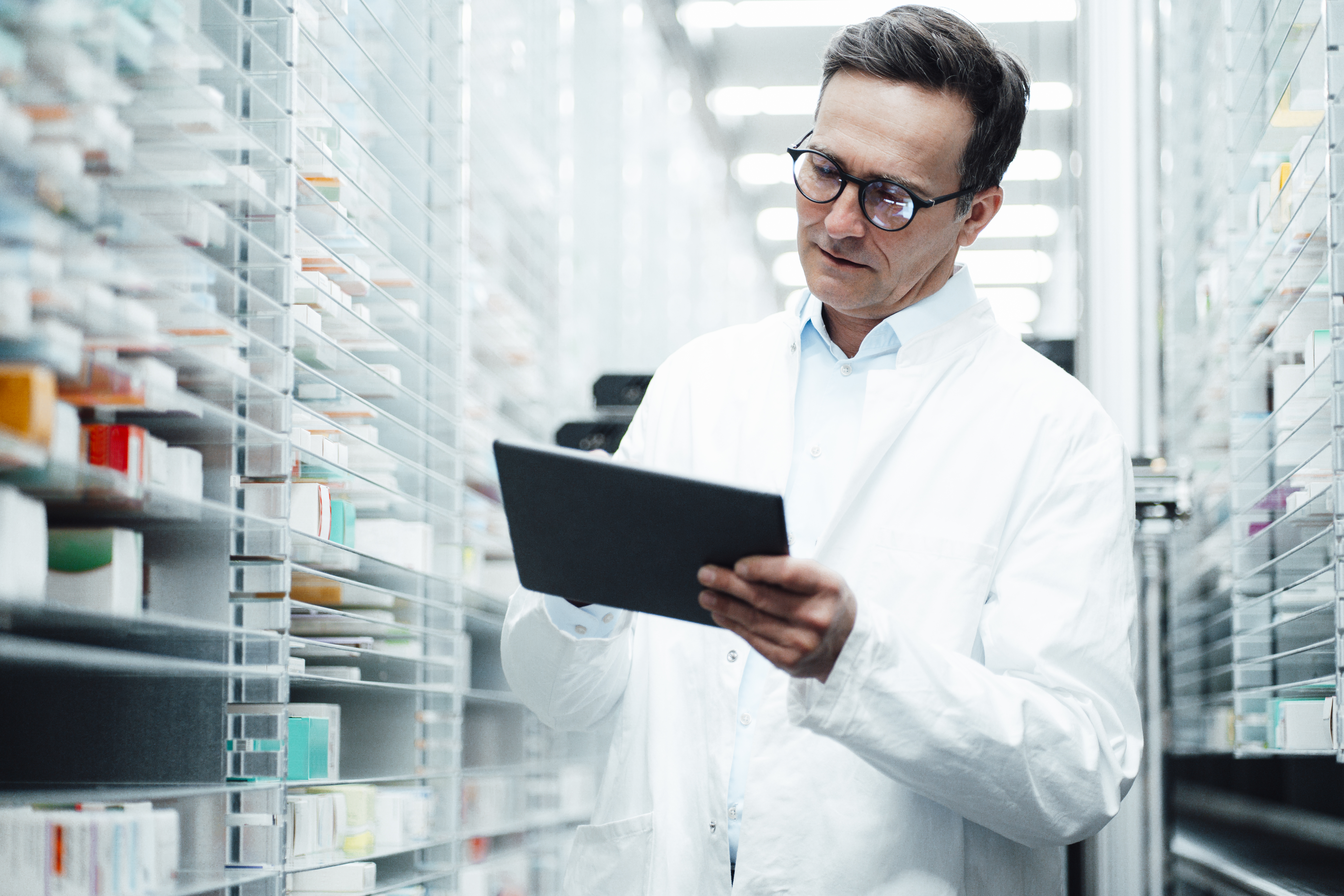 Pharmacist with tablet PC taking inventory in storage room