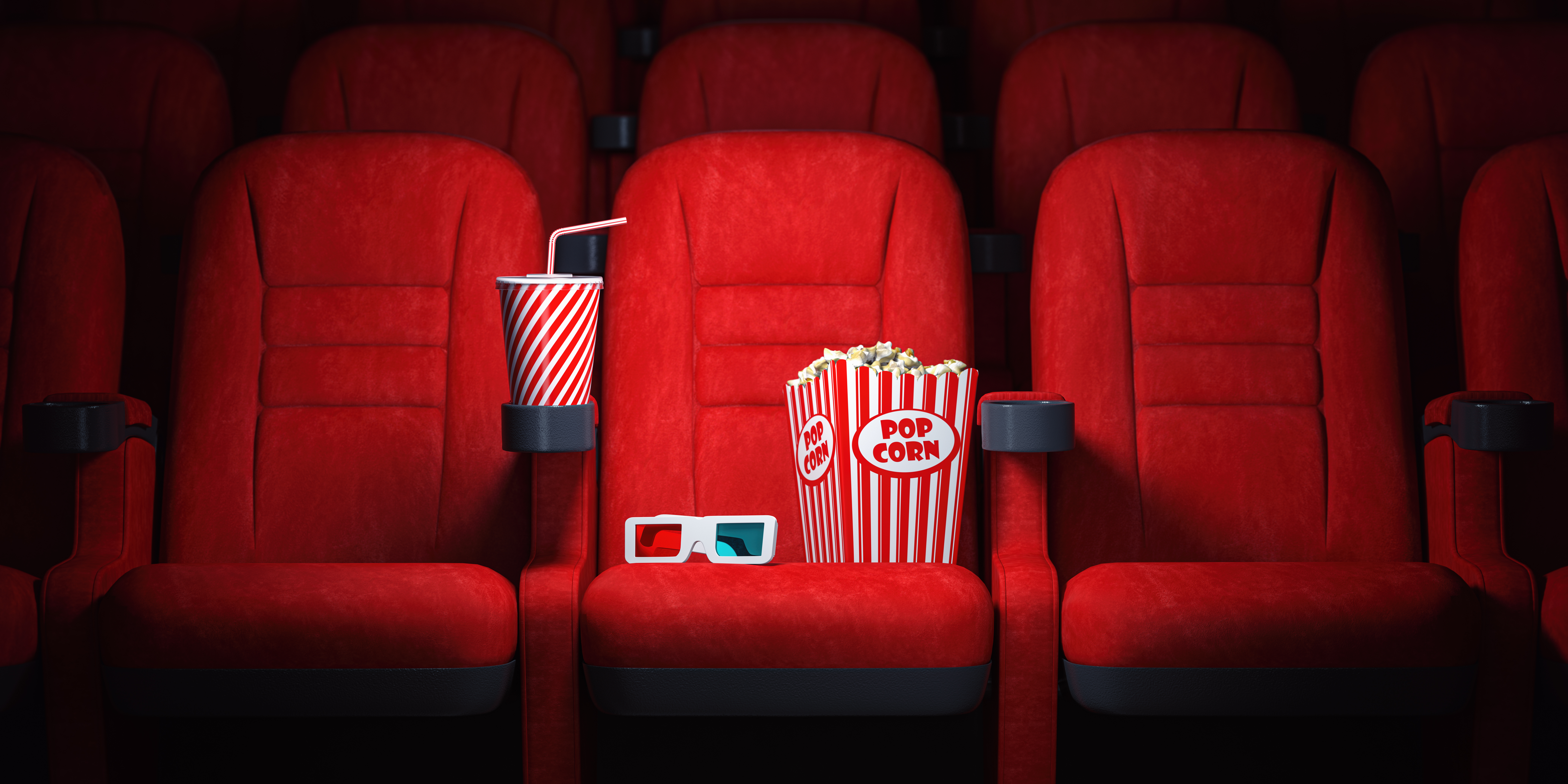 Red cinema seats and cola, popcorn and glasses in empty theater. Cinema movie theater concept background.