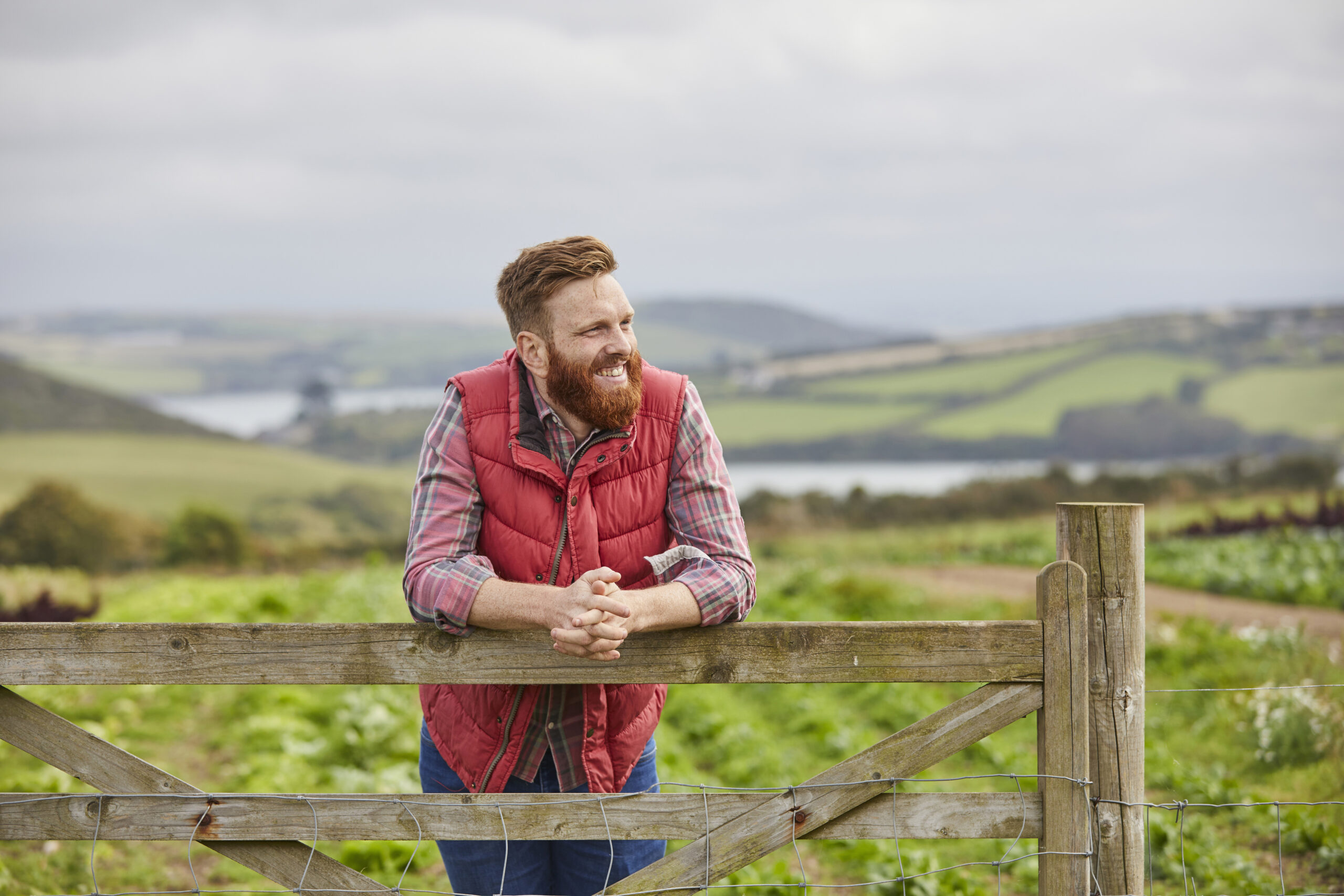 Man on farm leaning against gate looking away