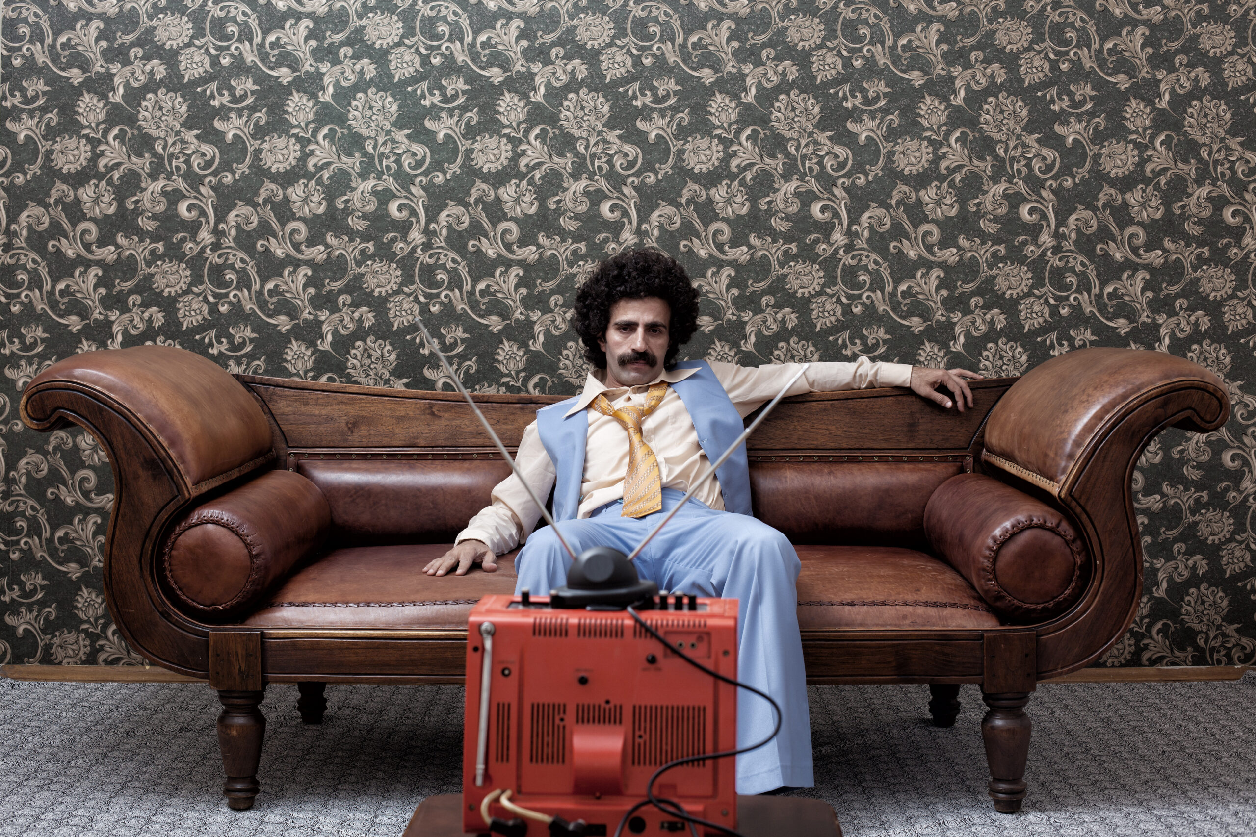 Man In 1970s Style Sitting On Sofa Watching Television